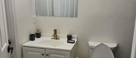 A bathroom with a white sink, a toilet, a mirror, and a towel rack.