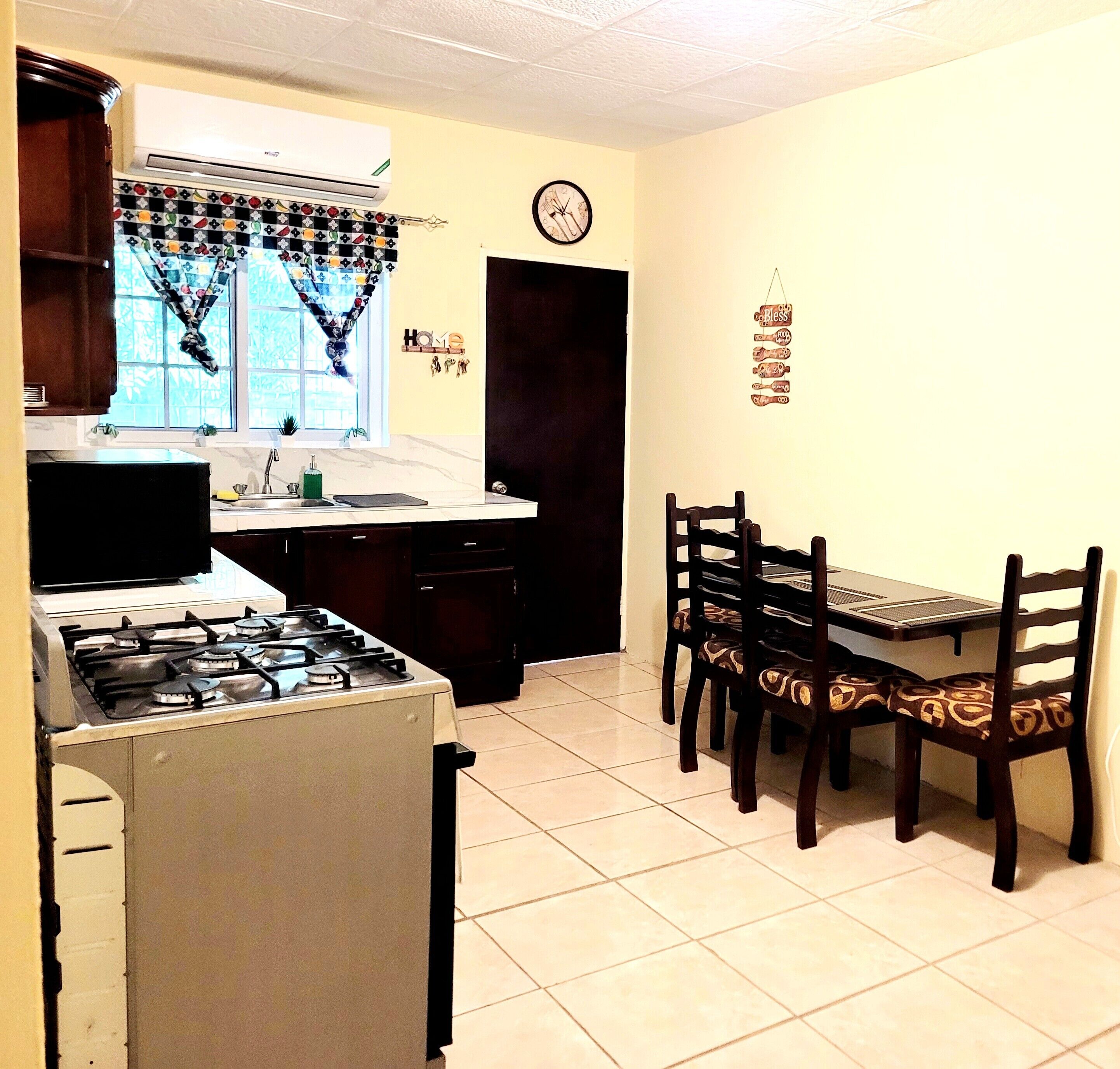 A kitchen with a stove, sink, and dining table with chairs.