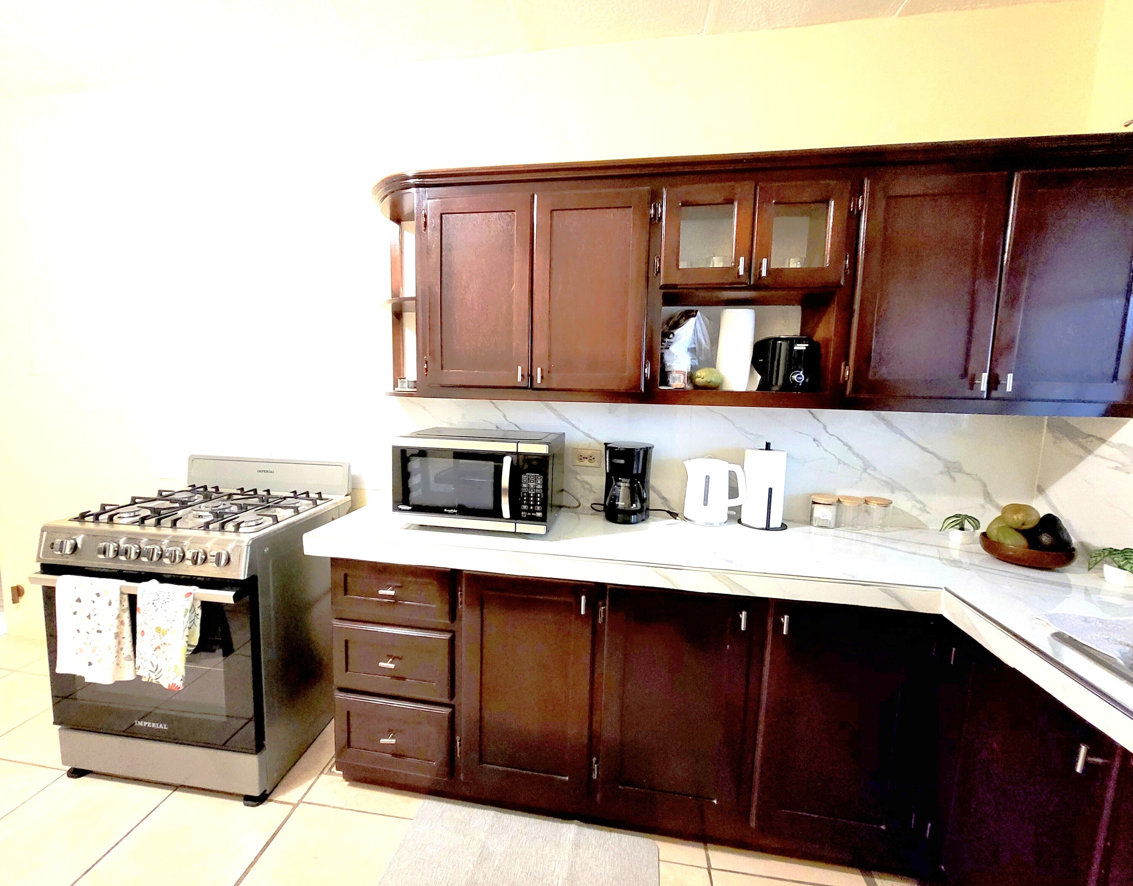 A kitchen with dark wooden cabinets, a gas stove, a microwave, and a coffee maker.