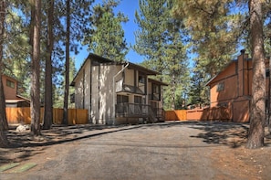 A cabin with a front porch, surrounded by tall pine trees, with a clear sky above. - Summit Après | 2-Min Walk to Snow Summit (Big Bear Lake)