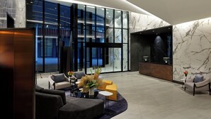 A modern lobby with seating, a reception desk, and large windows. - Executive Luxury Suite | The Well Toronto (Toronto)