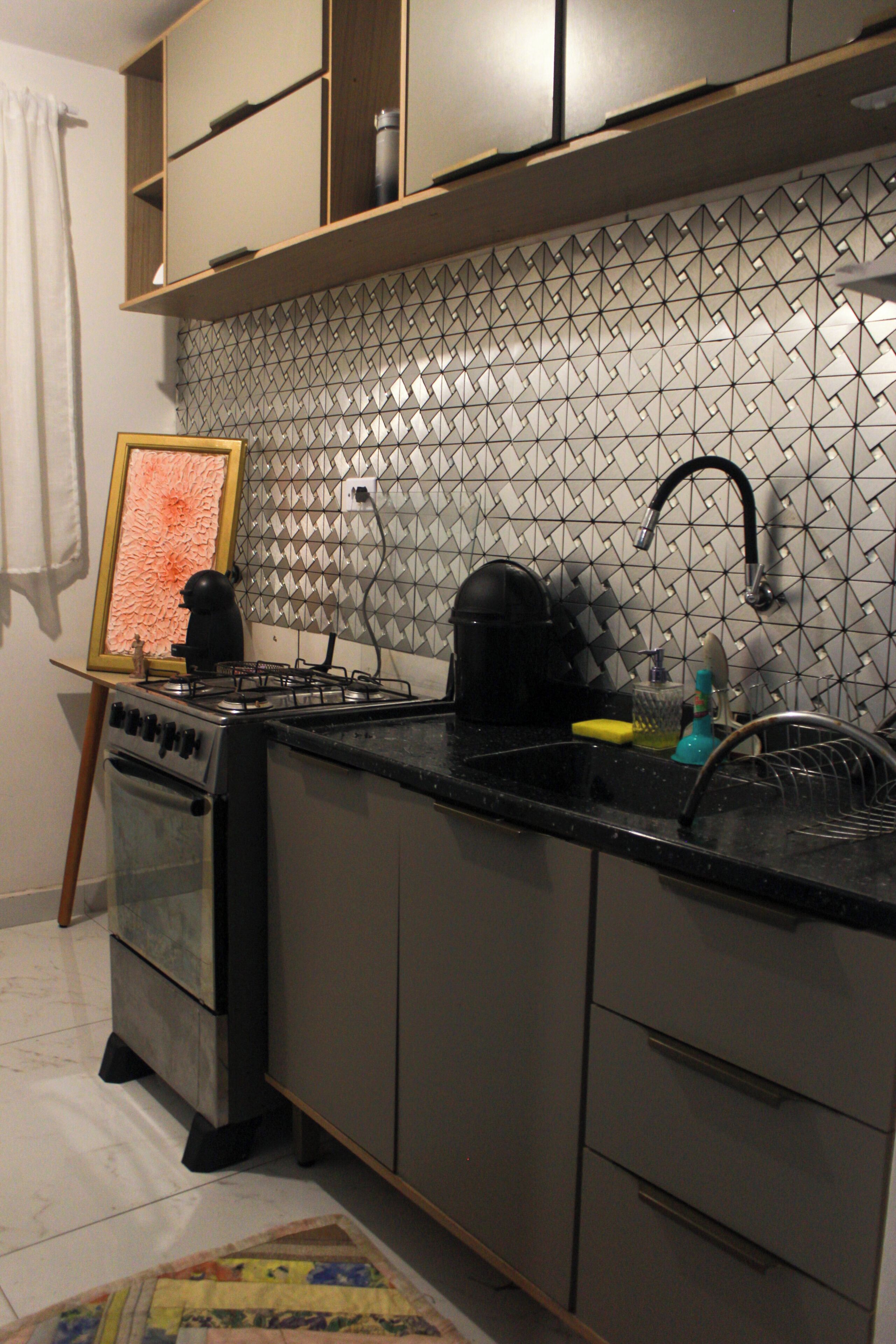 Uma cozinha com fogão a gás, pia e painel de azulejos.