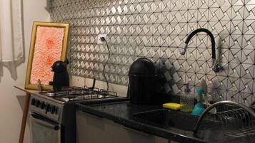 Uma cozinha com fogão a gás, pia e painel de azulejos.