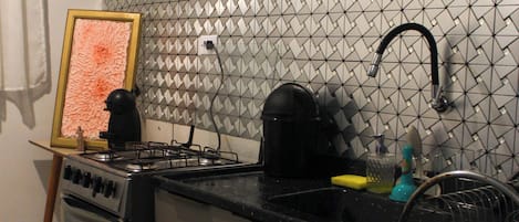 A kitchen with a gas stove, a sink, and a tiled backsplash.