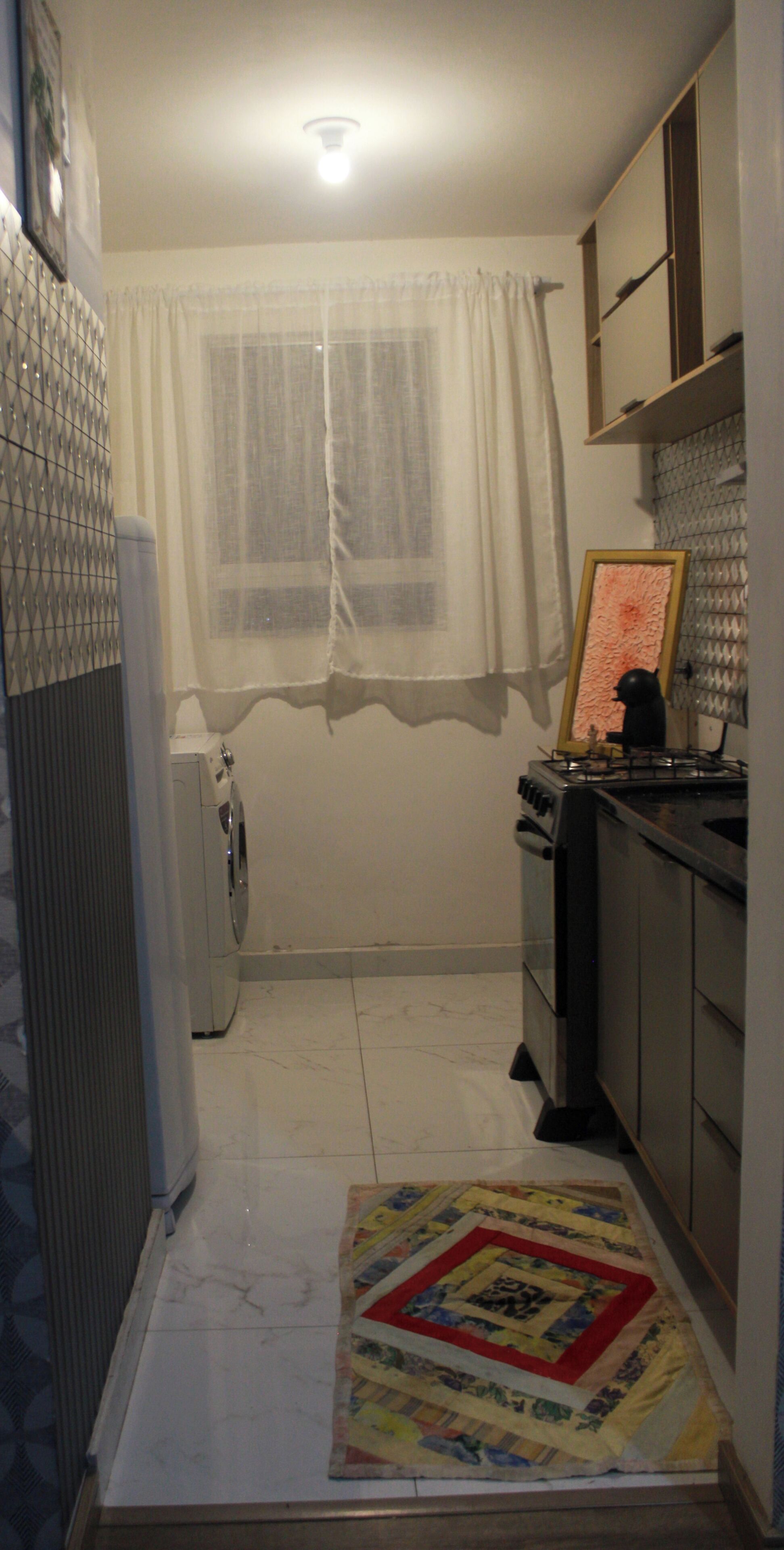 Cocina compacta con refrigerador, estufa y ventana con cortinas.