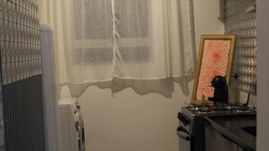 A compact kitchen with a refrigerator, stove, and a window with curtains.