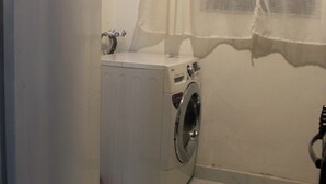 A laundry room with a washing machine and a large white appliance, possibly a dryer or washer, on a tiled floor.
