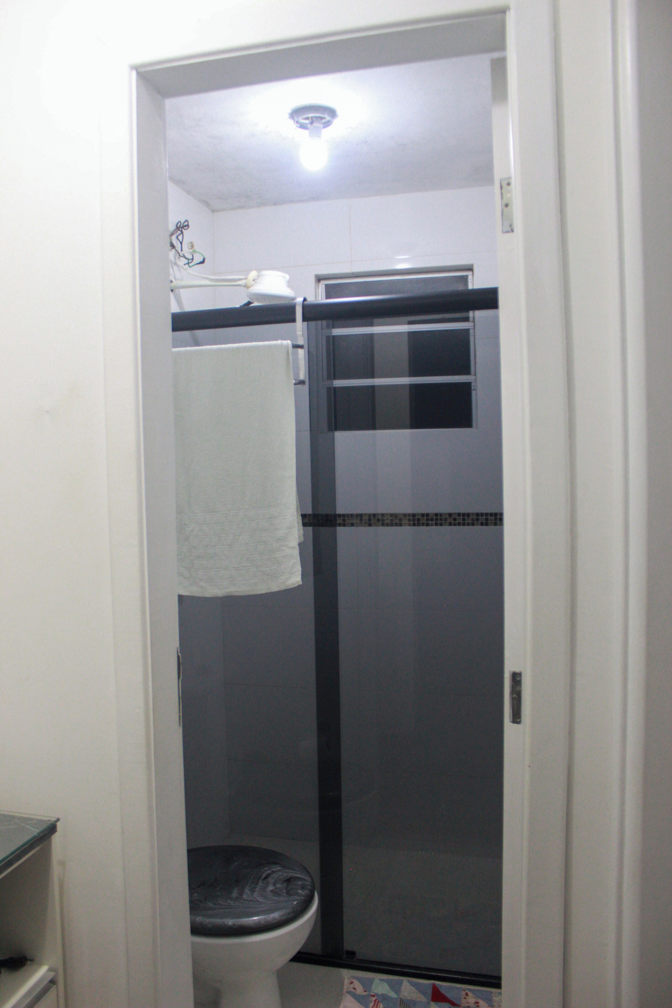 A bathroom with a toilet, a shower stall, and a towel hanging on a rack.