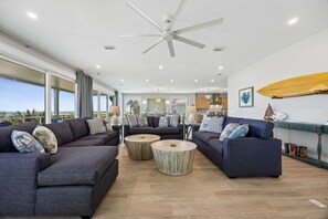 A modern living room with two sofas, a coffee table, and a ceiling fan.