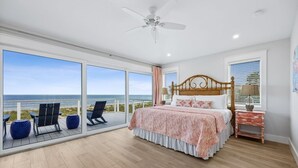 A bedroom with a large bed, a ceiling fan, a nightstand, and a view of the ocean. - Fin & Tonic | Brand New Oceanfront Beach House | Hot Tub | Elevator | EV Charger | Sleeps 18 (Fernandina Beach)