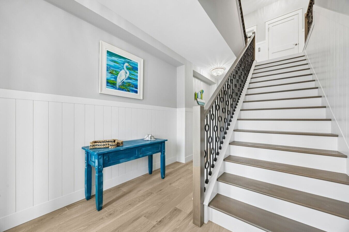Un escalier avec une rampe noire et une porte blanche en haut.