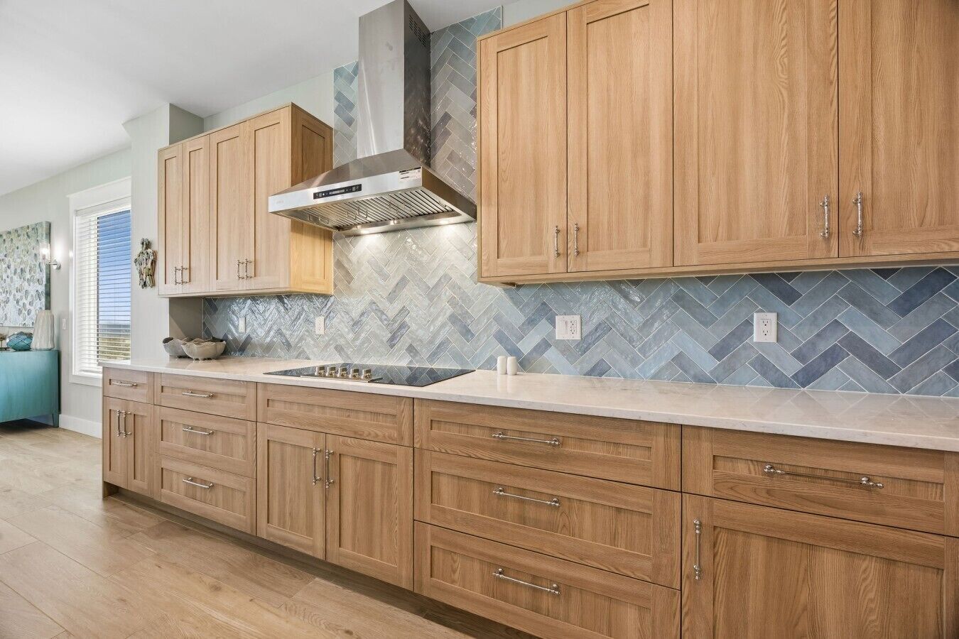 A kitchen with wooden cabinets, a stainless steel range hood, and a herringbone tile backsplash.