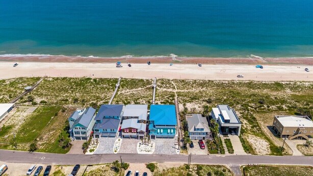 An aerial view of a coastal property with multiple buildings, a beach, and a road. - Fin & Tonic | Brand New Oceanfront Beach House | Hot Tub | Elevator | EV Charger | Sleeps 18 (Fernandina Beach)