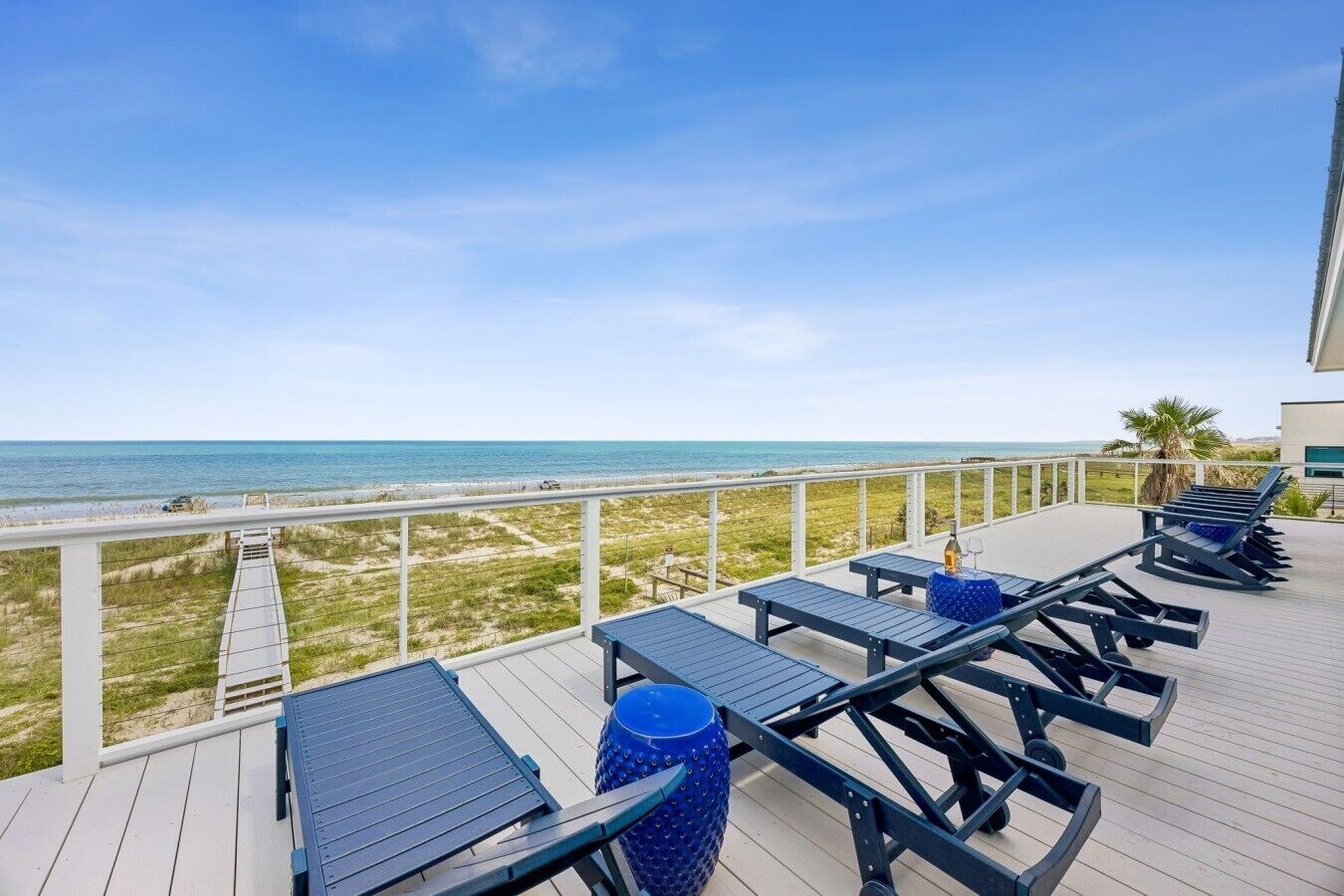 A deck with sun loungers and a view of the beach.