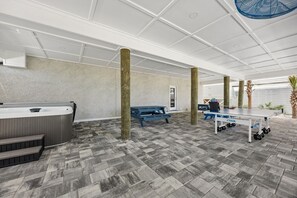 Amplio espacio interior con una recepción, un jacuzzi y una mesa de ping pong.