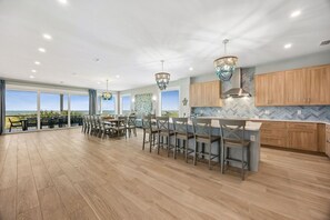 Una cocina amplia con armarios de madera, una isla grande con taburetes de bar y vista al océano.