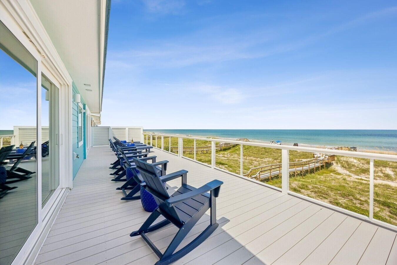 A deck with outdoor seating and a view of the beach.