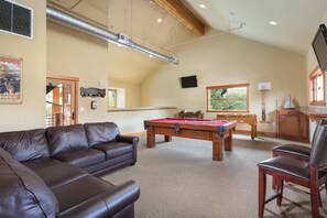 Ein Wohnzimmer mit Billardtisch, Ledersofa und Holzschrank.