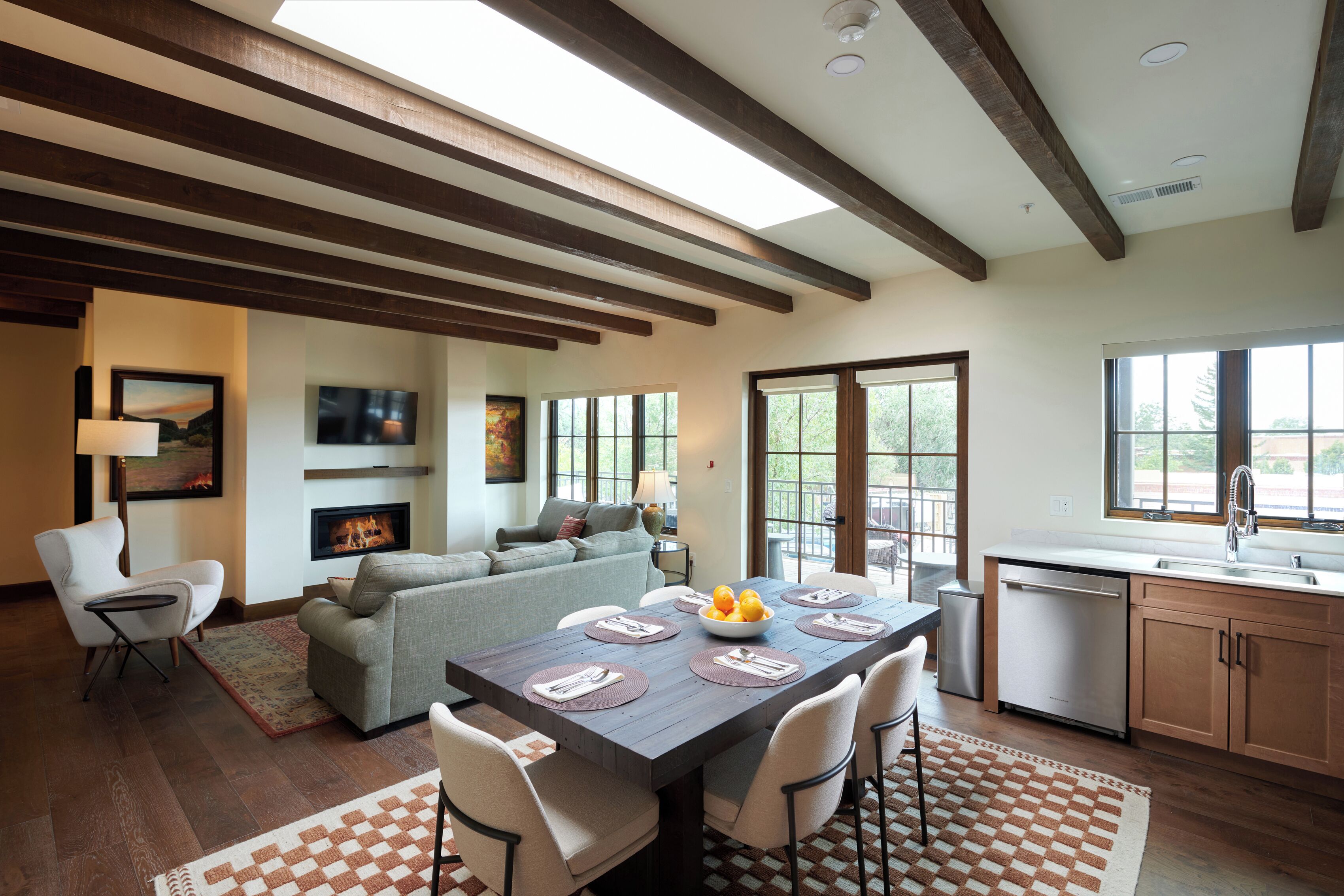 A modern living space with a dining area, kitchen, and a fireplace.