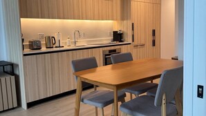 A modern kitchen with wooden cabinets, a built-in oven, and a dining area with a wooden table and chairs. - Spacious 1BR Condo in Downtown Miami | Sleep 4 (Miami)