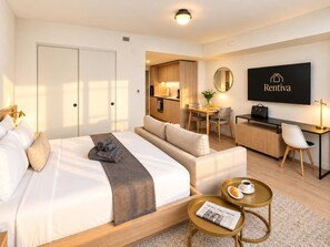 A hotel room with a bed, a desk, a chair, a small table with a newspaper, and a television on the wall. - Spacious 1BR Condo in Downtown Miami | Sleep 4  | Free Parking (Miami)