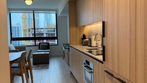 A modern kitchen with wooden cabinets, a built-in oven, and a window overlooking a construction site. - Spacious 1BR Condo in Downtown Miami | Sleep 4 (Miami)