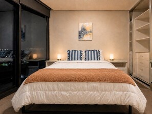 A bedroom with a bed, bedside tables, a nightstand, a window with a city view, and a wardrobe. - Sydney Olympic Park Panorama 3B2B by WinsonHome (Sydney Olympic Park)