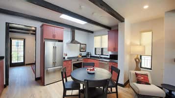 Uma cozinha moderna com ilha central, eletrodomésticos de aço inoxidável e área de jantar com mesa redonda e cadeiras.