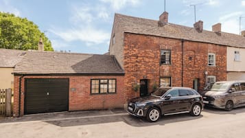 A two-story brick building with a garage, a car parked in front, and a clear sky.