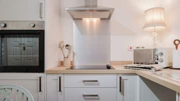 A modern kitchen with a built-in oven, a stainless steel range hood, and a countertop with a kettle and a toaster.