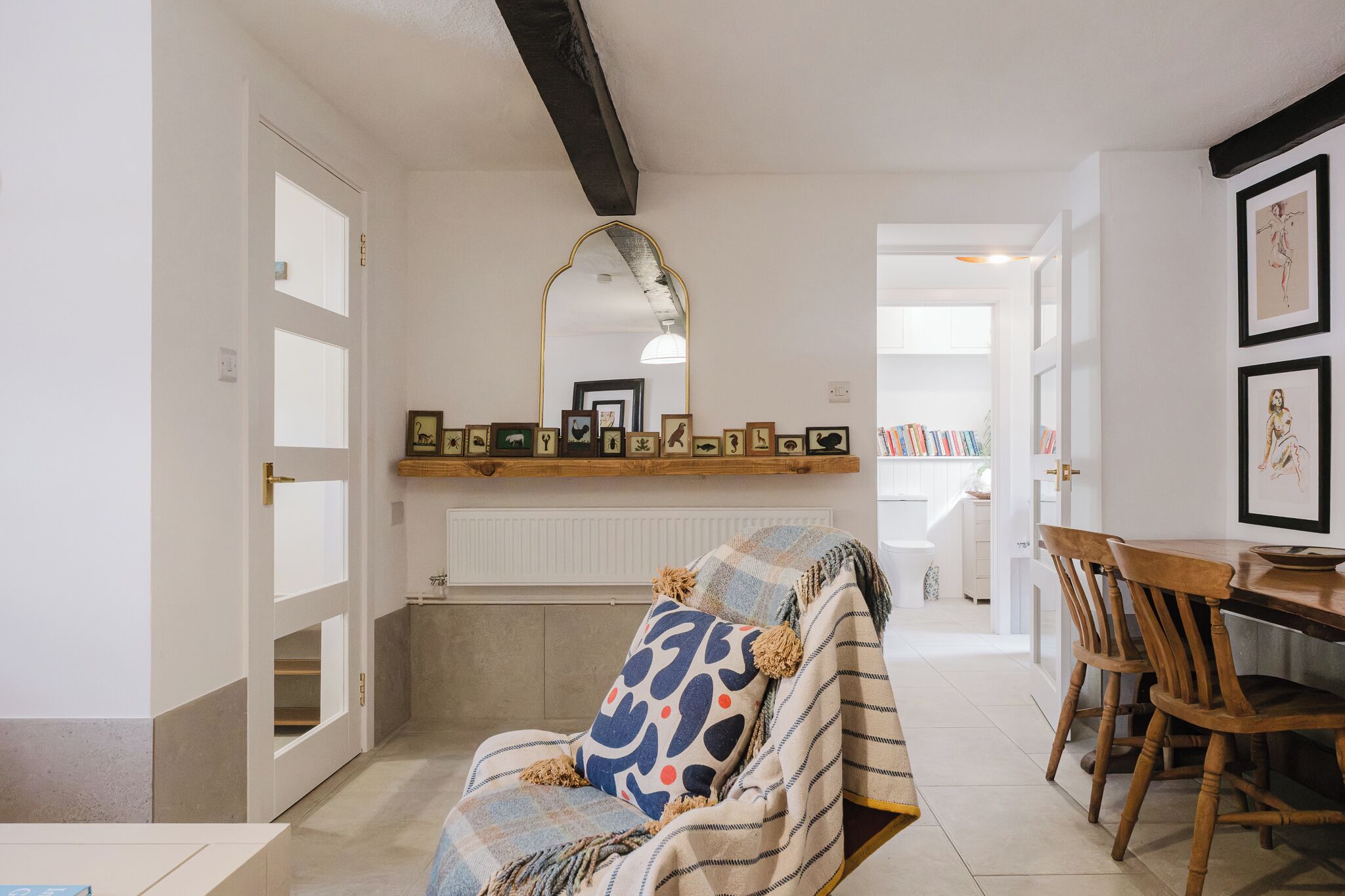 Una sala de estar acogedora con sofá, una mesa de comedor con sillas, chimenea y un pasillo que conduce a otra habitación.