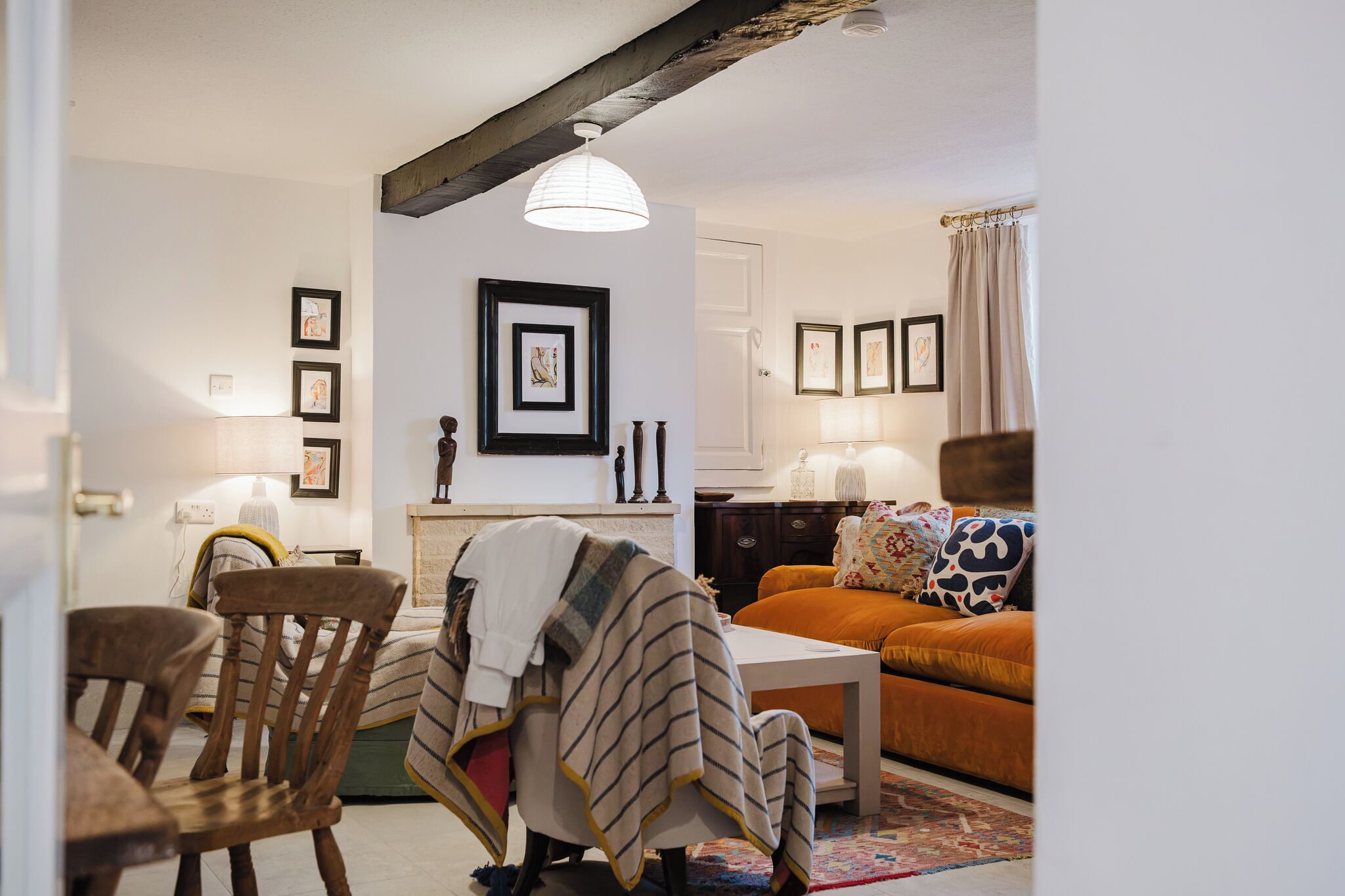 A living room with a fireplace, a sofa, a dining table with chairs, and artwork on the walls.