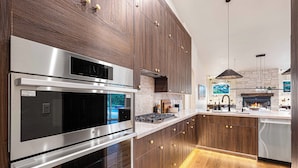 Eine moderne Küche mit Edelstahlgeräten, Holzschränken und einer Steinwand.