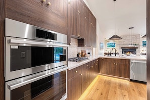 Eine moderne Küche mit Edelstahlgeräten, Holzschränken und einer Steinwand.