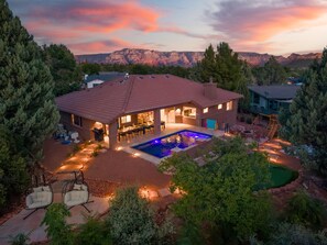 A house with a swimming pool, patio seating, and a mountain view.