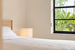 A bed with white bedding, a wooden headboard, and a bedside lamp. - Renovated 1BR w Private Garden & Laundry (Miami Shores)