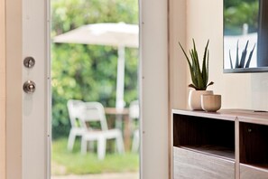 A view through a glass door into an outdoor area with a white chair and a table under a white umbrella. - Renovated 1BR w Private Garden & Laundry (Miami Shores)