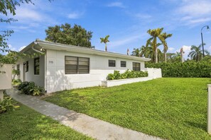 A single-story residential building with a flat roof, a front entrance, and a number '715' displayed on the wall. - Renovated 1BR w Private Garden & Laundry (Miami Shores)