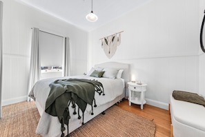 A bedroom with a bed, bedside table, and a hanging macrame wall decoration.