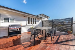 A rooftop patio with a barbecue grill, a table, and four chairs.