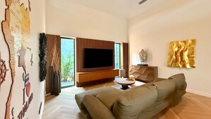 Un soggiorno moderno con una grande TV a schermo piatto, un divano e un elemento decorativo a parete.