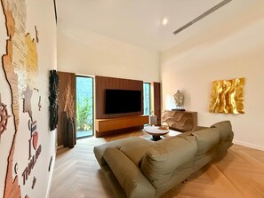 Ein modernes Wohnzimmer mit einem großen Flachbildfernseher, einem Sofa und einem dekorativen Wandbild.