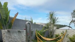 A swimming pool with a built-in water feature, a white safety sign, and a hammock. - Villa Amara - Viluma Villas (Hua Hin)