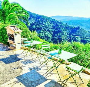 An outdoor seating area with a stone grill, green folding chairs, and a table with a vase. - La Marginella, Intera Villa • Toscana • 14 pax (Pescia)