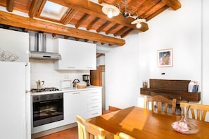 A kitchen with white cabinets, a wooden dining table, and a hanging light fixture. - La Marginella, Intera Villa • Toscana • 14 pax (Pescia)