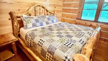 A wooden cabin bedroom with a bed, a nightstand, and a window.
