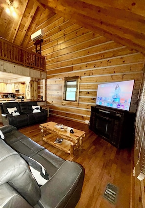 A log cabin interior with a wooden ceiling, a living room with a sofa set, a coffee table, and a television. - Tight Hollow Escape RRG•UTV Park• Hot Tub• Pond for Fishing• Sleeps 9 Pool Table (Pine Ridge)