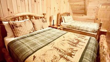 A wooden cabin bedroom with two beds, a nightstand, and a lamp.