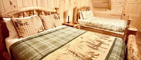 Un dormitorio de cabaña de madera con dos camas, una mesita de noche y una lámpara.