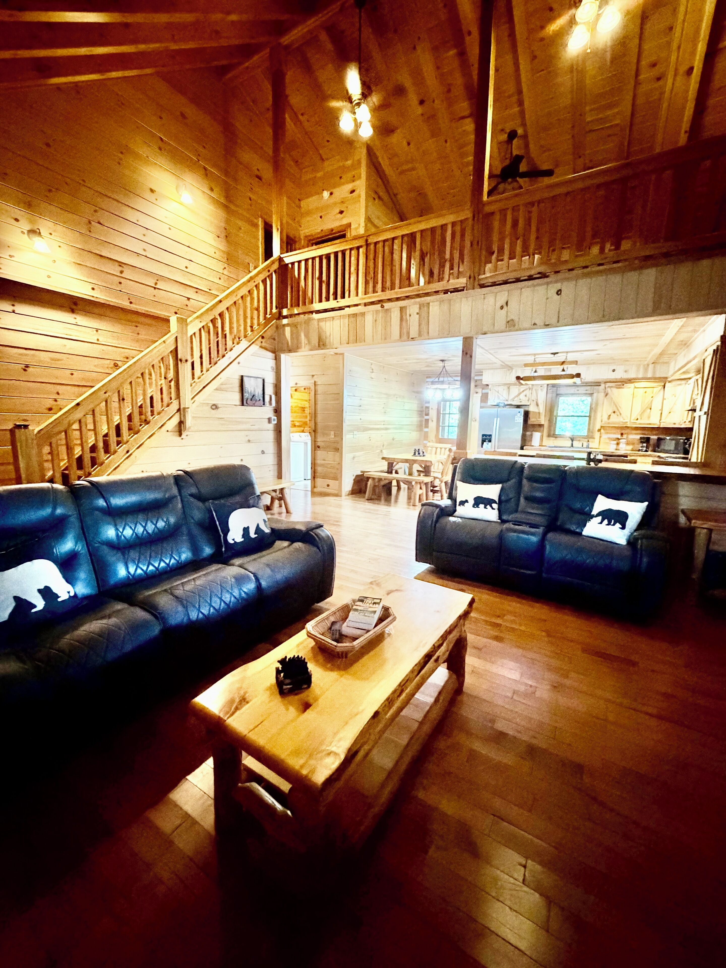 A spacious living area with two leather sofas, a wooden coffee table, and a staircase leading to an upper level.